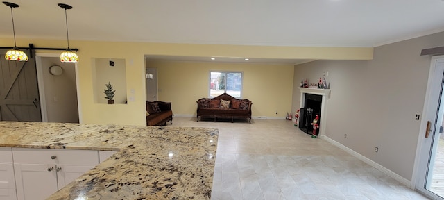 kitchen with baseboards, white cabinets, light stone counters, ornamental molding, and a fireplace