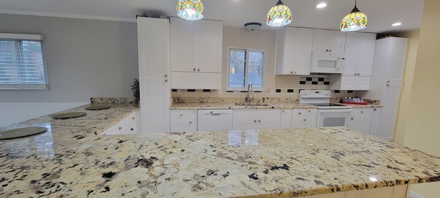 kitchen with light stone counters, a peninsula, white appliances, a sink, and backsplash