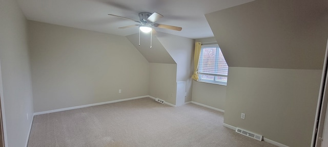 additional living space with visible vents, a ceiling fan, carpet flooring, vaulted ceiling, and baseboards