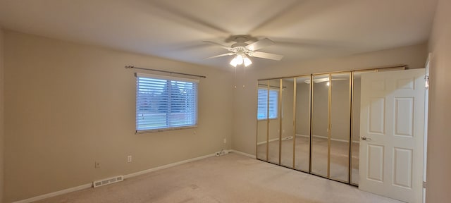 unfurnished bedroom with a ceiling fan, light colored carpet, visible vents, and baseboards