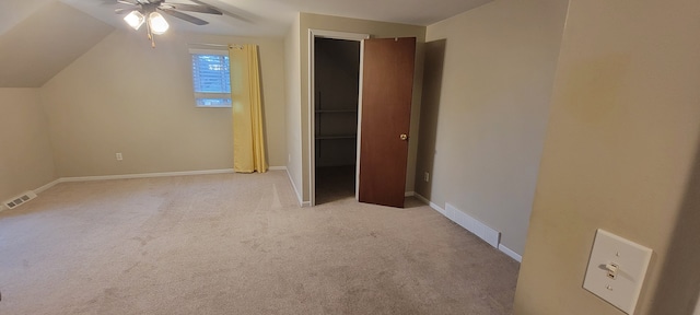 unfurnished bedroom featuring light colored carpet, visible vents, lofted ceiling, and baseboards