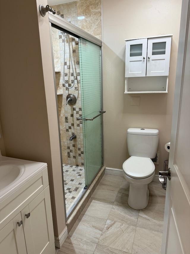 bathroom with a stall shower, vanity, toilet, and baseboards