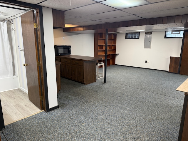 interior space featuring a paneled ceiling, electric panel, and baseboards