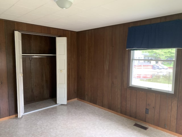 7004 Walnut Hill Rd, Manitou Beach, MI 49253 - unfurnished bedroom featuring wooden walls, a closet, and baseboards