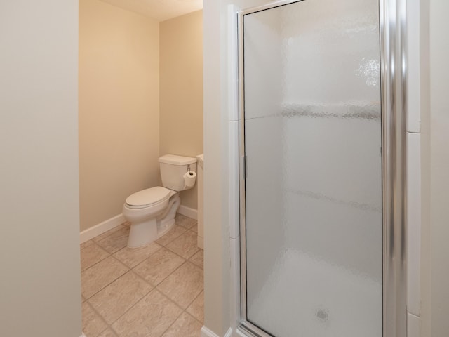 full bath with a stall shower, baseboards, tile patterned flooring, and toilet