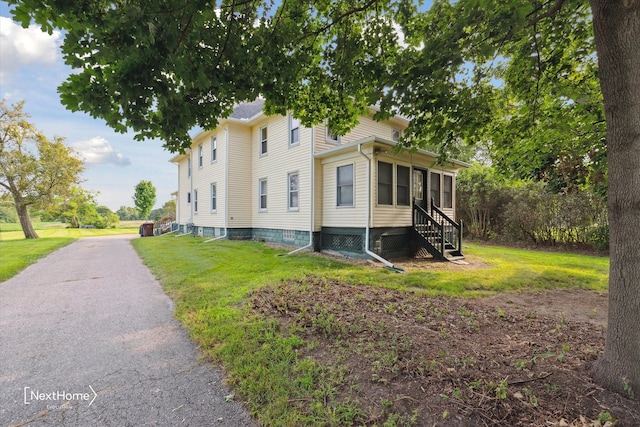 view of home's exterior featuring entry steps and a lawn