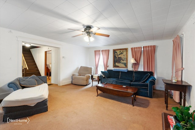 living room featuring a ceiling fan, carpet flooring, baseboards, and stairs