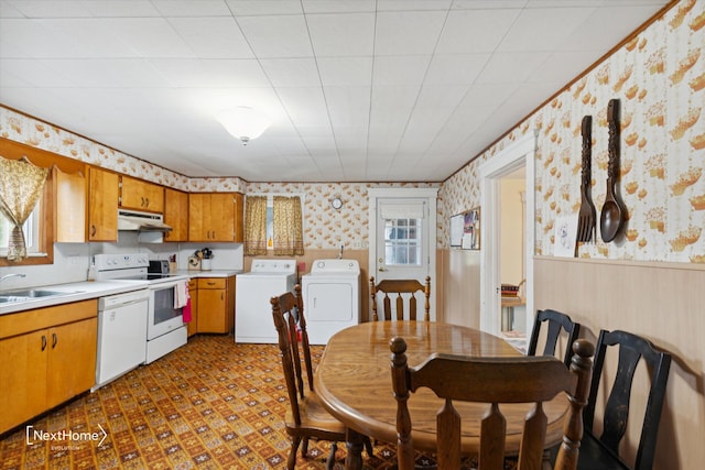 kitchen featuring a wainscoted wall, under cabinet range hood, white appliances, and wallpapered walls