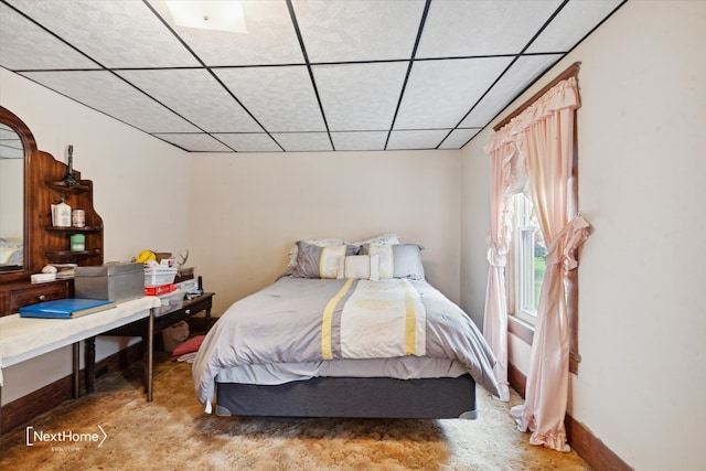 bedroom featuring a paneled ceiling and baseboards