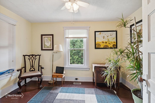 sitting room with baseboards, visible vents, a ceiling fan, wood finished floors, and a textured ceiling