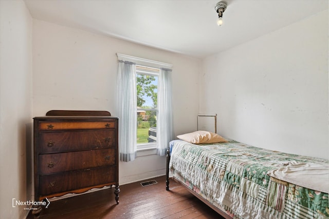 bedroom with hardwood / wood-style flooring, visible vents, and baseboards