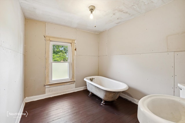 bathroom with a freestanding bath, baseboards, and hardwood / wood-style flooring