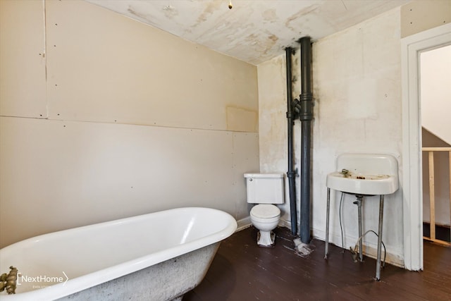 bathroom with a freestanding bath, wood finished floors, and toilet