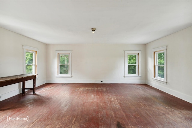 empty room featuring wood-type flooring, plenty of natural light, and baseboards