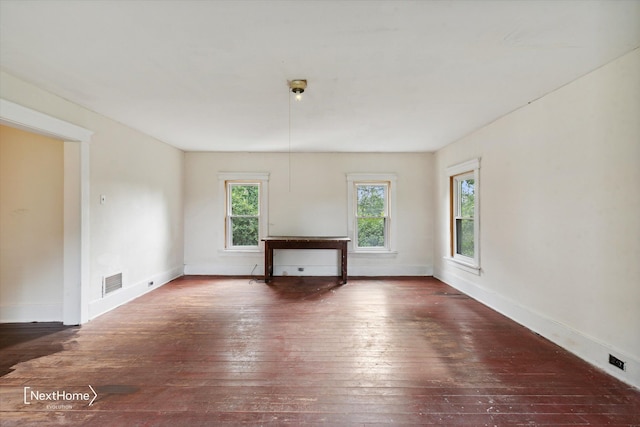 unfurnished living room featuring baseboards, visible vents, and hardwood / wood-style floors