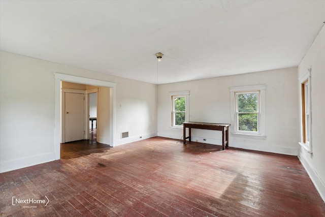 spare room with wood-type flooring, visible vents, and baseboards