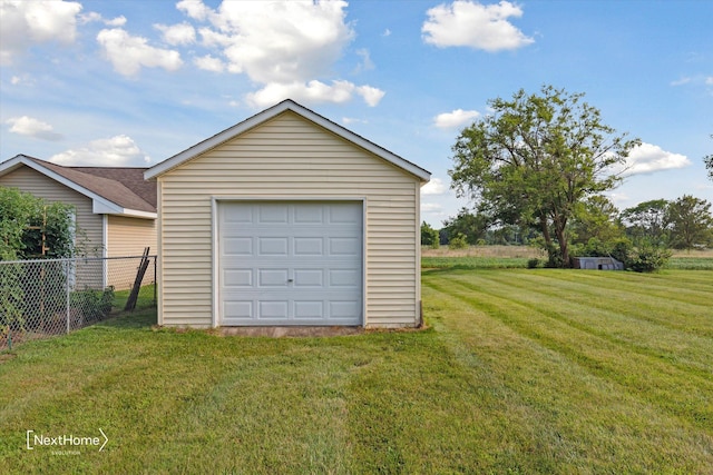 detached garage featuring driveway and fence