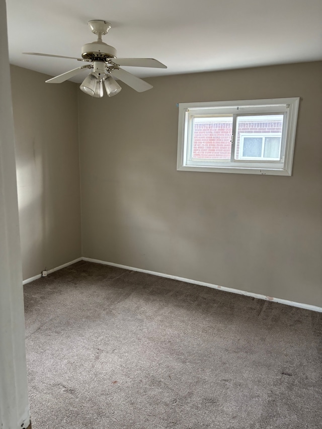 carpeted spare room with ceiling fan and baseboards