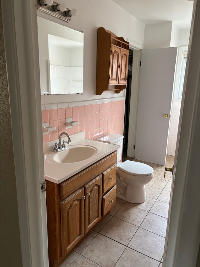 bathroom with tile patterned flooring, toilet, a wainscoted wall, vanity, and tile walls