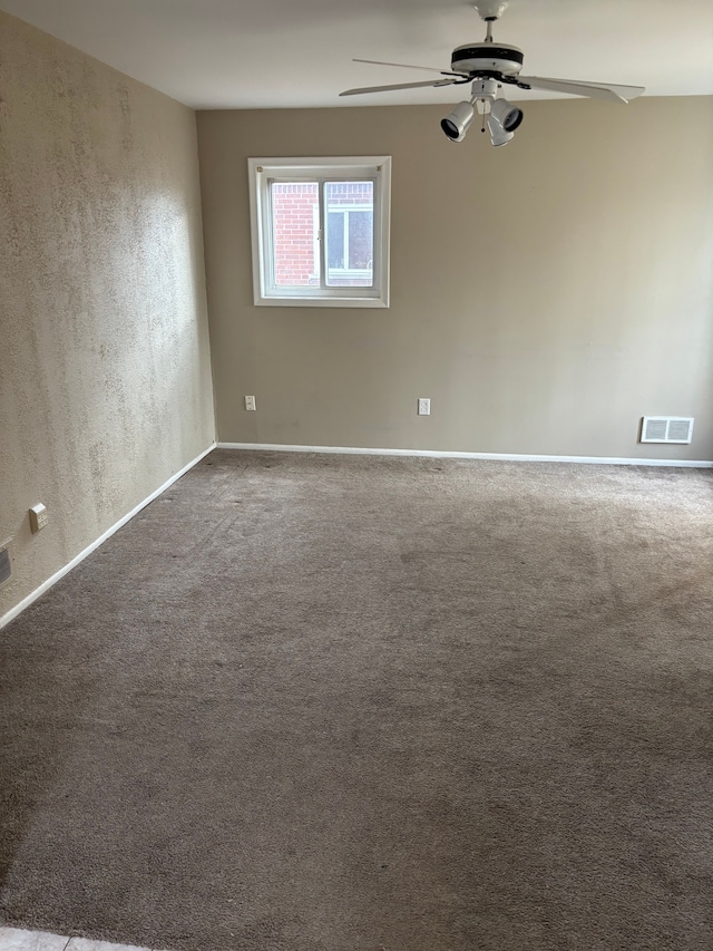 spare room with carpet floors, baseboards, visible vents, and a ceiling fan