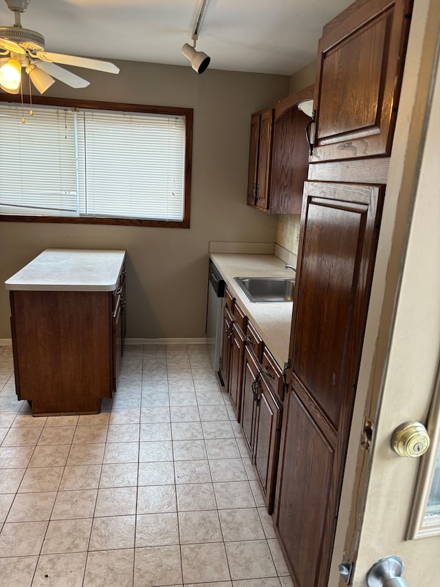 kitchen featuring dishwasher, light countertops, light tile patterned floors, and a sink