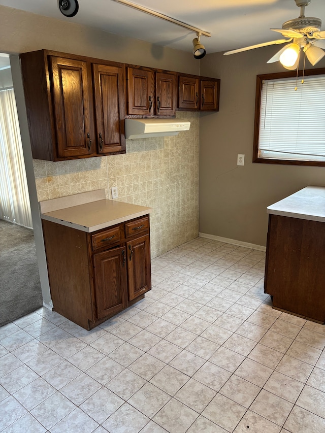 kitchen with light tile patterned floors, ceiling fan, under cabinet range hood, light countertops, and dark brown cabinets