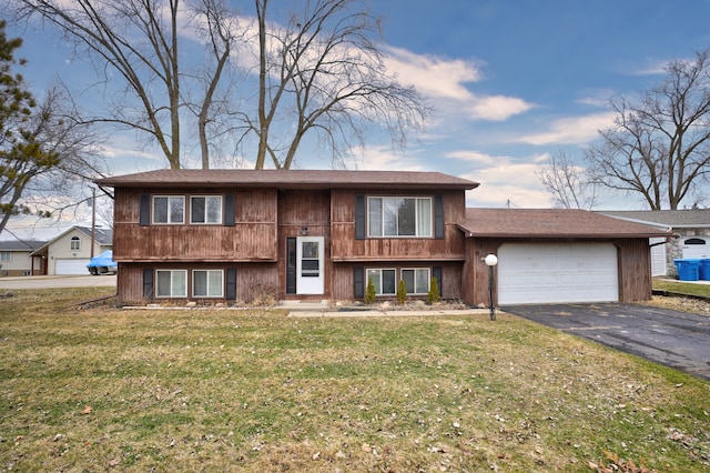 raised ranch featuring a garage, driveway, and a front yard