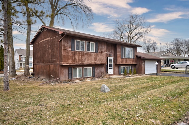 raised ranch with a garage, a front lawn, and aphalt driveway