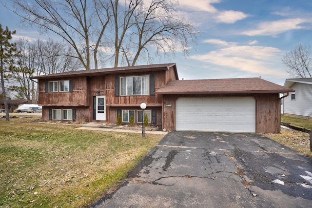 raised ranch with driveway, a front lawn, and an attached garage