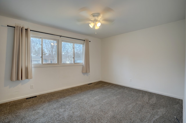 unfurnished room featuring baseboards, visible vents, dark carpet, and ceiling fan