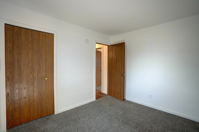 unfurnished bedroom with a closet, baseboards, and carpet flooring