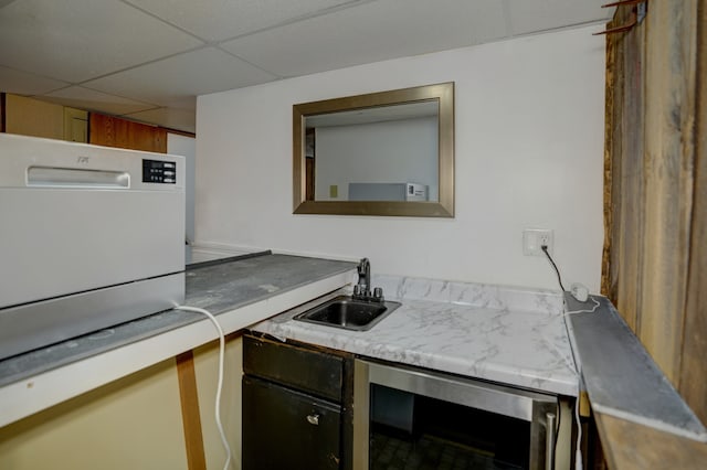 kitchen featuring wine cooler, light countertops, a sink, and a paneled ceiling