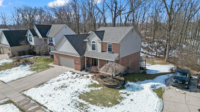 traditional-style home with driveway, an attached garage, a shingled roof, and brick siding