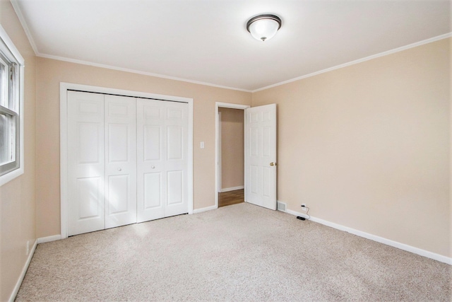 unfurnished bedroom featuring a closet, baseboards, carpet flooring, and ornamental molding