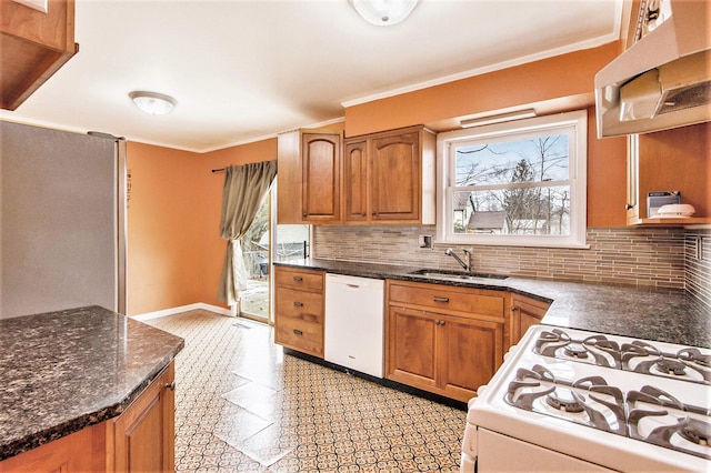 kitchen featuring white appliances, crown molding, brown cabinetry, and a sink