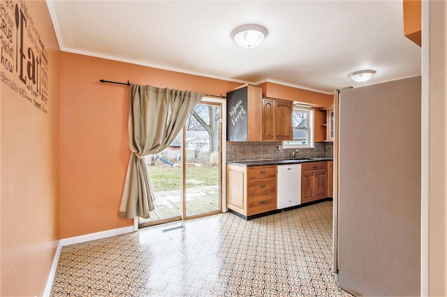 kitchen with white dishwasher, a sink, baseboards, tasteful backsplash, and dark countertops