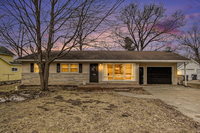 ranch-style home with stone siding, an attached garage, and driveway