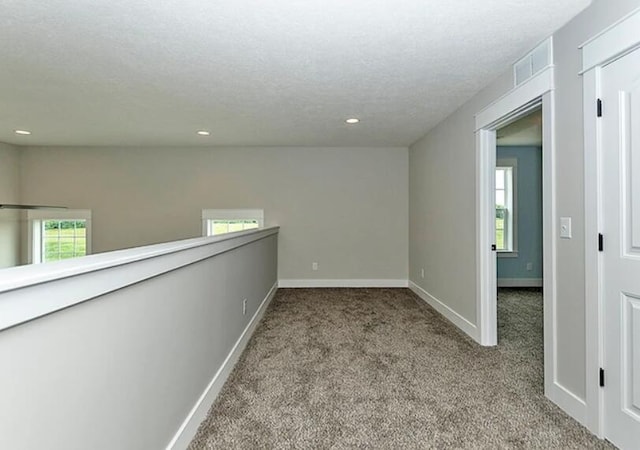 carpeted spare room featuring visible vents, baseboards, a textured ceiling, and recessed lighting