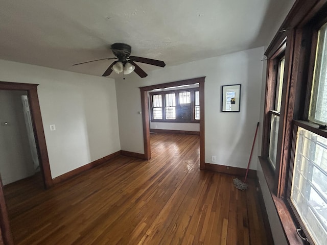 empty room featuring dark wood-style floors, baseboards, and a ceiling fan