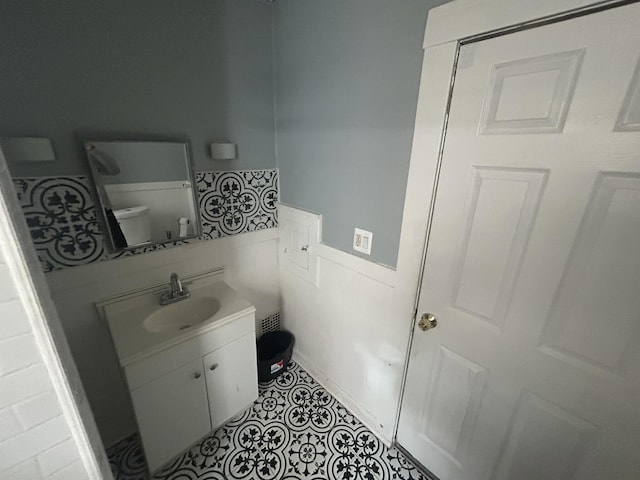 bathroom featuring toilet, a wainscoted wall, vanity, and tile patterned floors