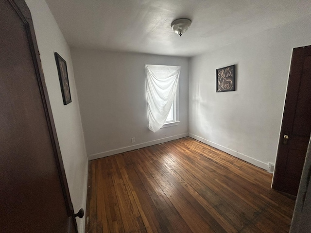 empty room featuring visible vents, hardwood / wood-style flooring, and baseboards