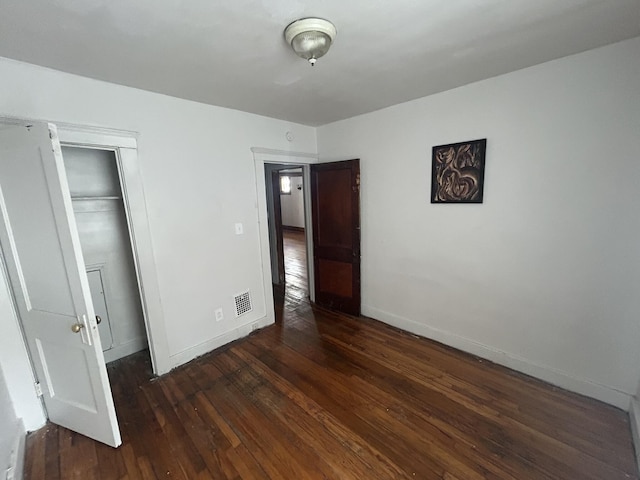 unfurnished bedroom with a closet, baseboards, visible vents, and hardwood / wood-style floors