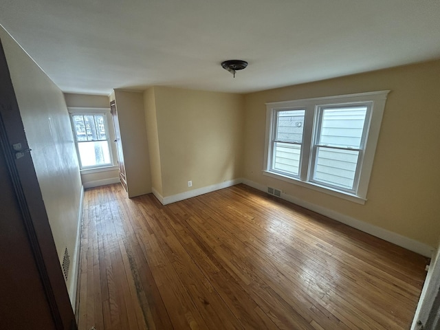 empty room with visible vents, baseboards, and hardwood / wood-style floors