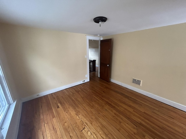 empty room featuring visible vents, baseboards, and wood finished floors