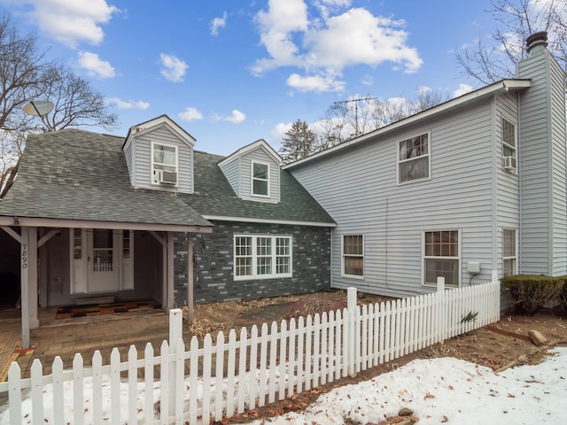 view of front of property featuring roof with shingles, brick siding, and a fenced front yard