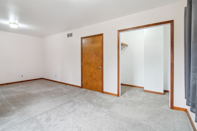 unfurnished bedroom with carpet floors, baseboards, a spacious closet, and visible vents