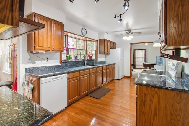 kitchen featuring range hood, brown cabinets, a sink, light wood-type flooring, and white appliances