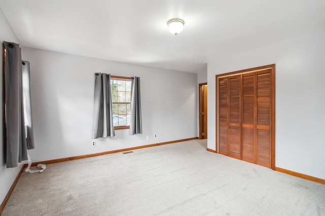 unfurnished bedroom with carpet, a closet, visible vents, and baseboards