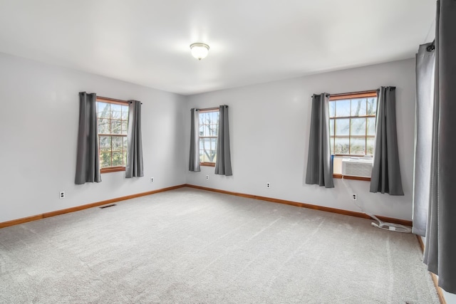 carpeted empty room with cooling unit, visible vents, and baseboards