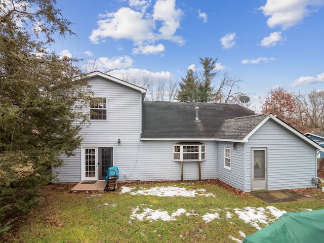 rear view of house with a lawn and roof with shingles